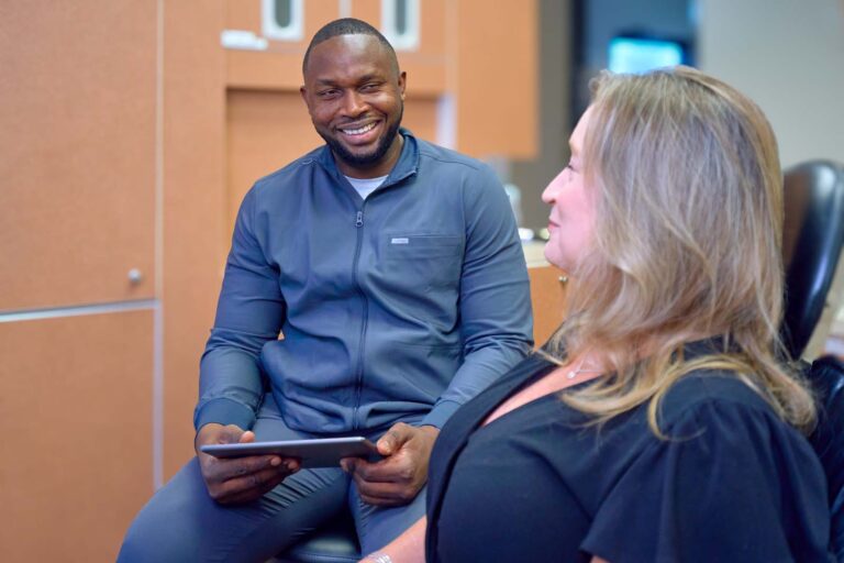 Smiling dental professional consulting with a patient using a tablet in the clinic.